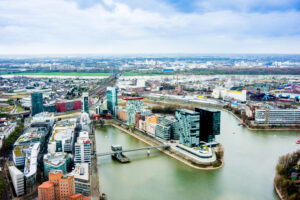 Aerial view of Dusseldorf cityscape with river, diverse architecture, and urban development.